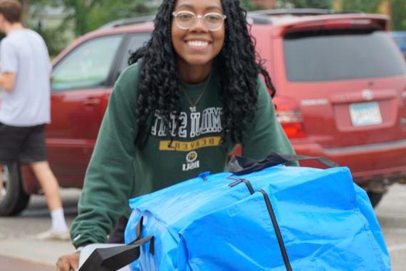 College student pushing a bin full of packages on move in day 2022